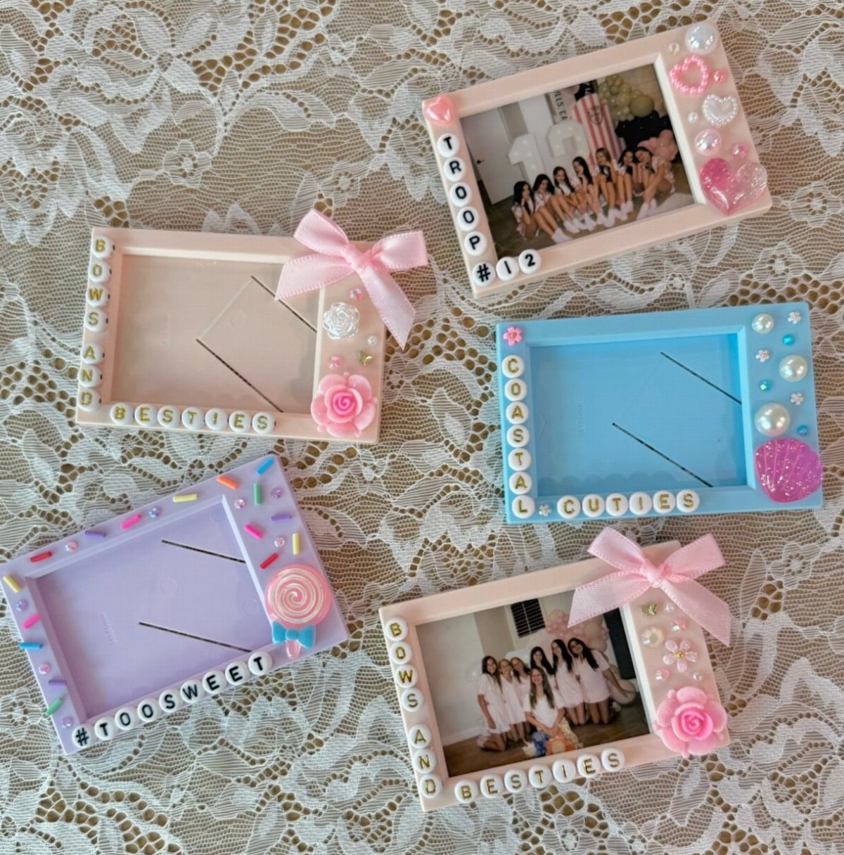 Colorful decorative photo frames with beads and bows on a white lace background.