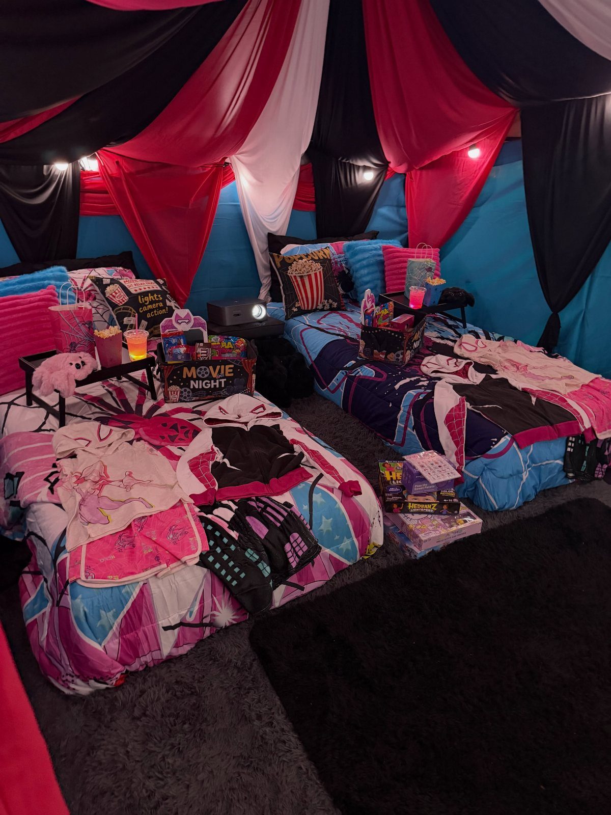 Two beds with colorful bedding under a draped canopy for a movie night.