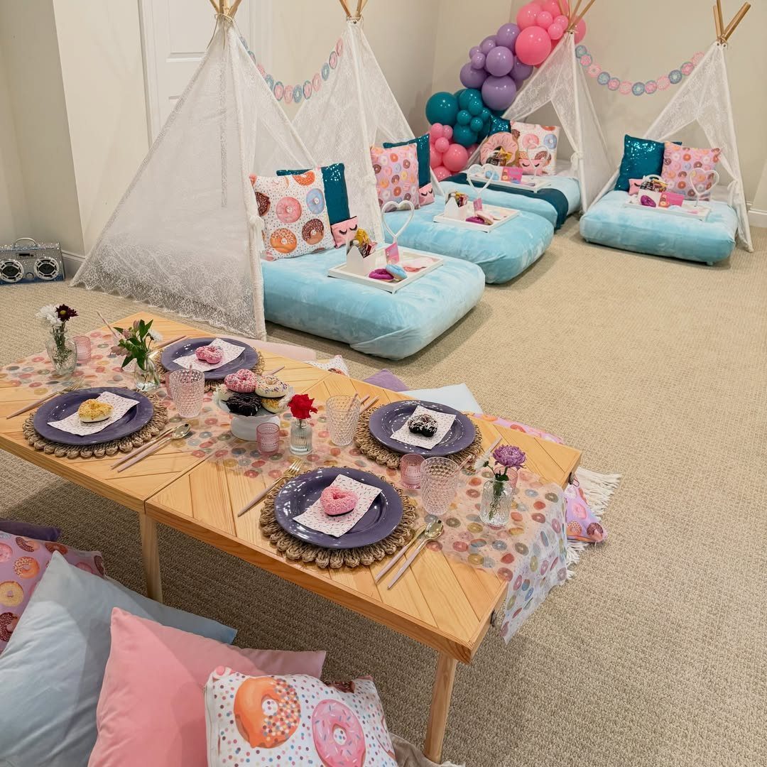 Donut themed sleepover party with white teepees, blue cushions, and donut decorations.
