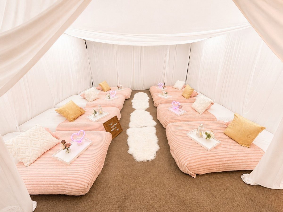 Pink ribbed mattresses with gold pillows and heart lights in a white draped room