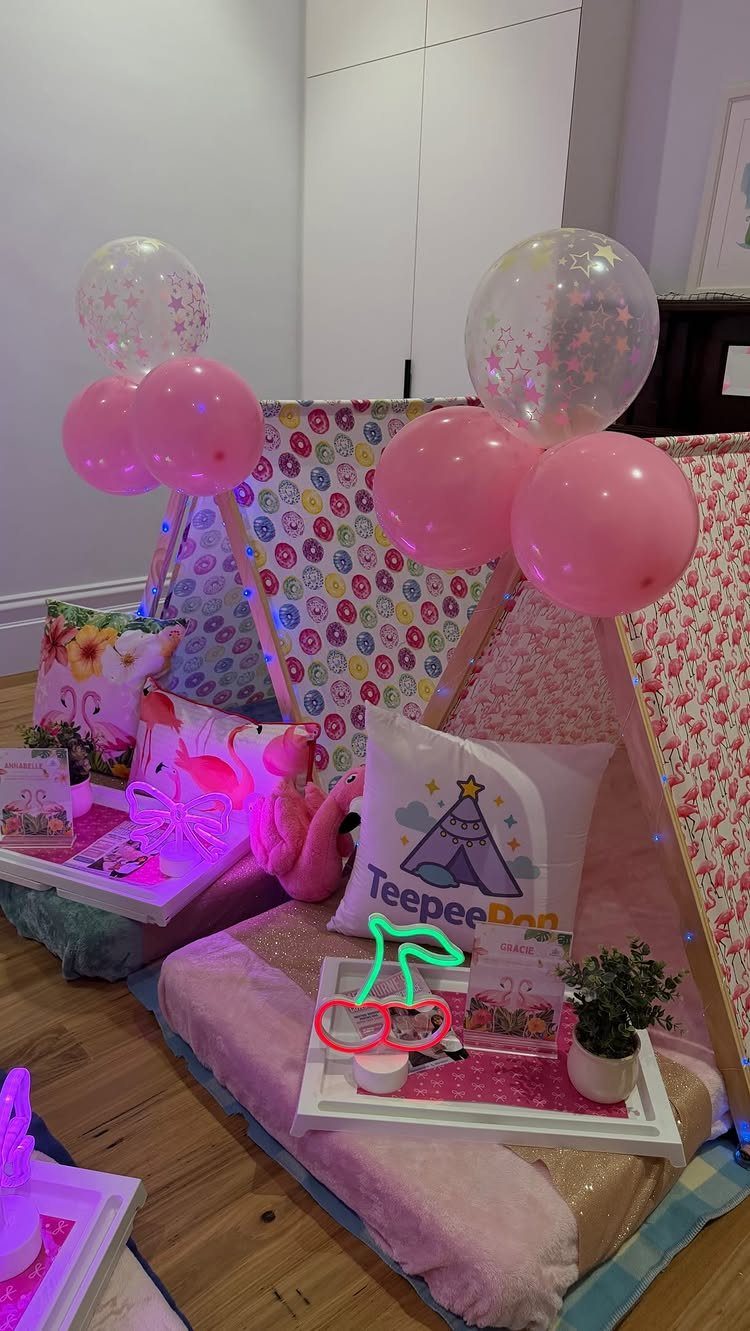Pink sleepover teepee setup with flamingo neon light, pink balloons, and plush pillows.