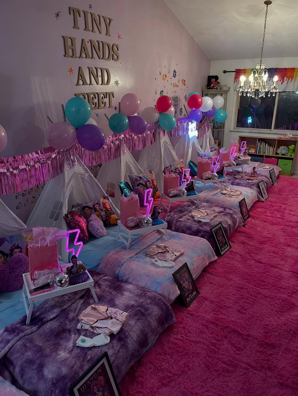 Row of white teepee tents with purple bedding on a pink shag carpet.