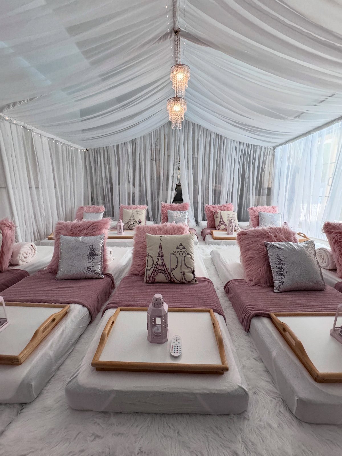 Three floor mattresses with pink bedding and a pillow featuring the word Paris.