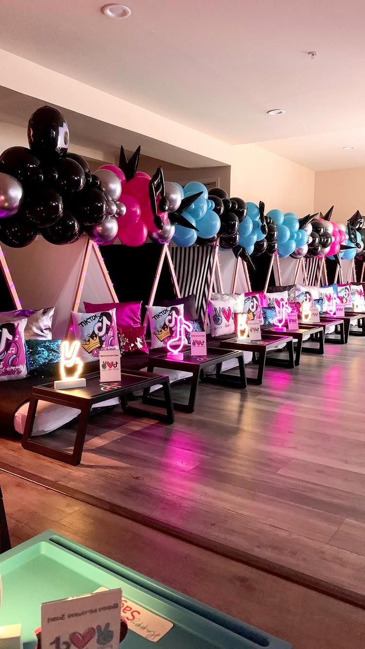 Teepee tents with TikTok logo pillows and colorful balloons for a slumber party.