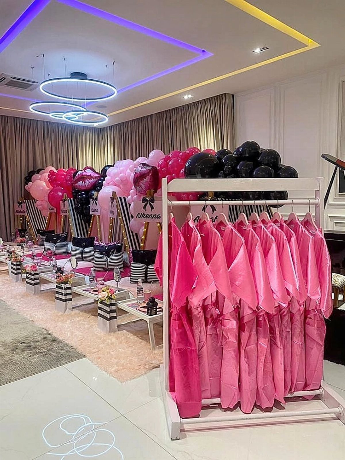 Pink satin robes on a white rack with pink and black balloons background