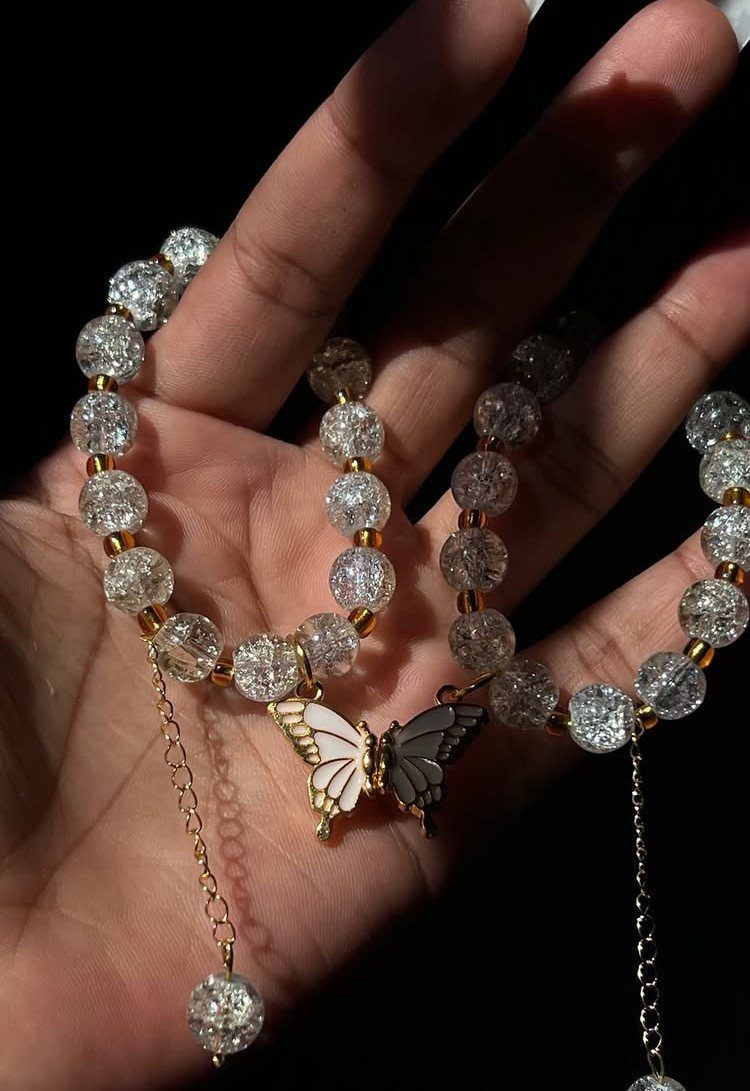 Two sparkling crystal beaded bracelets with a butterfly charm resting on a palm.