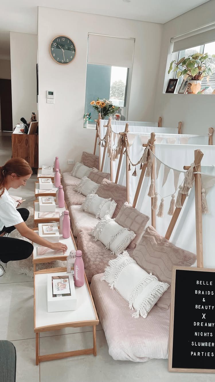 Row of pink teepees with white pillows and bedside tables for a slumber party.