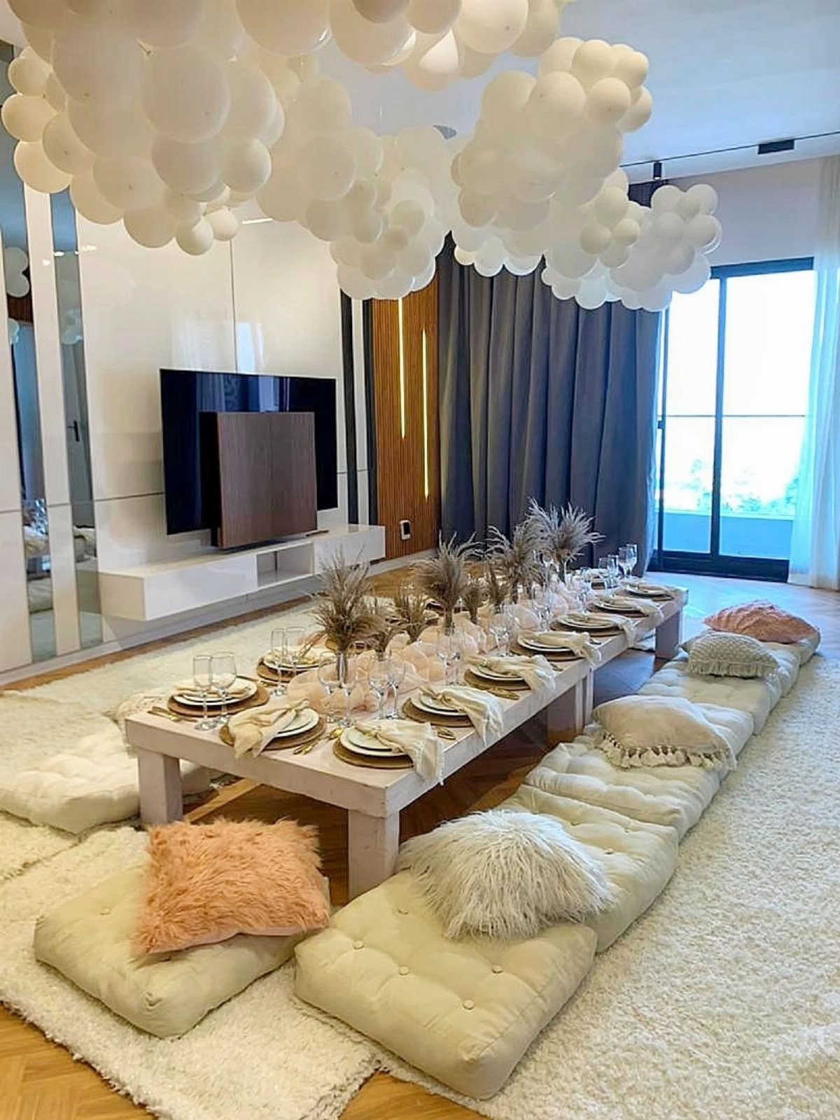 Low white dining table with floor cushions and white balloon clouds on ceiling