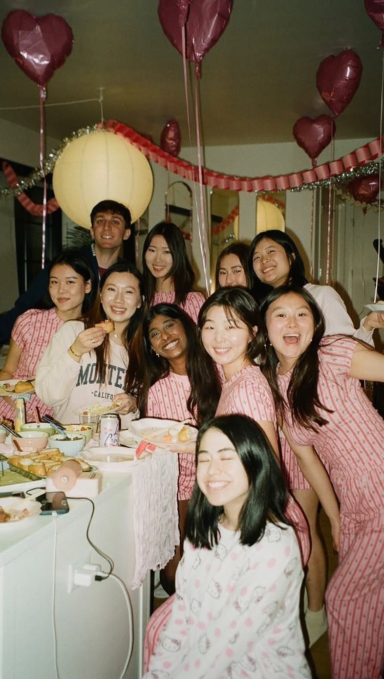 Group of friends in pink pajamas posing at a decorated slumber party.