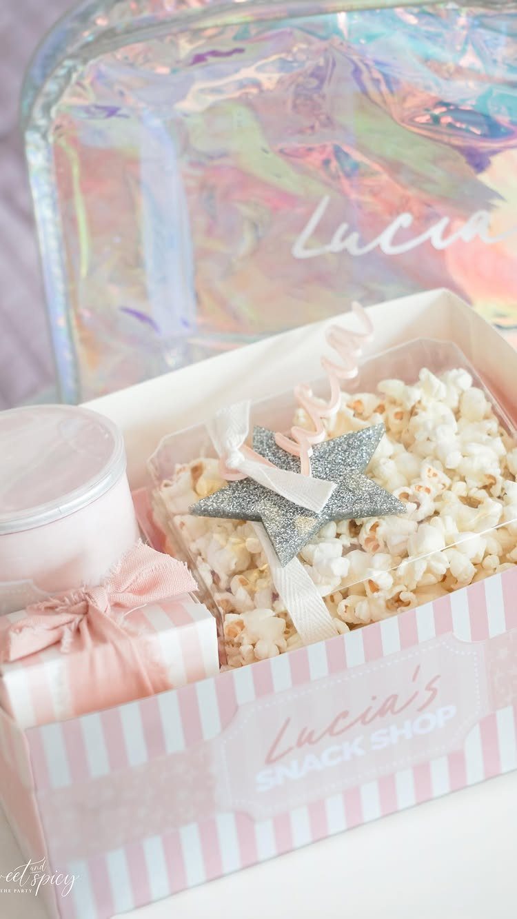 Popcorn in a pink striped snack box next to a holographic bag.
