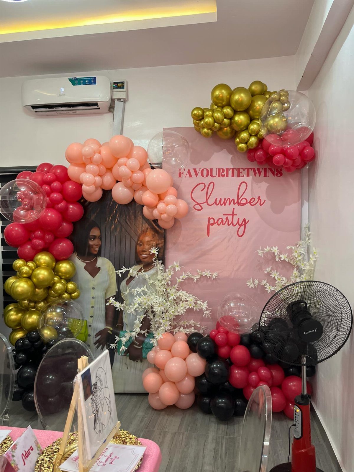 Pink slumber party backdrop with gold and pink balloon arches and floral accents.