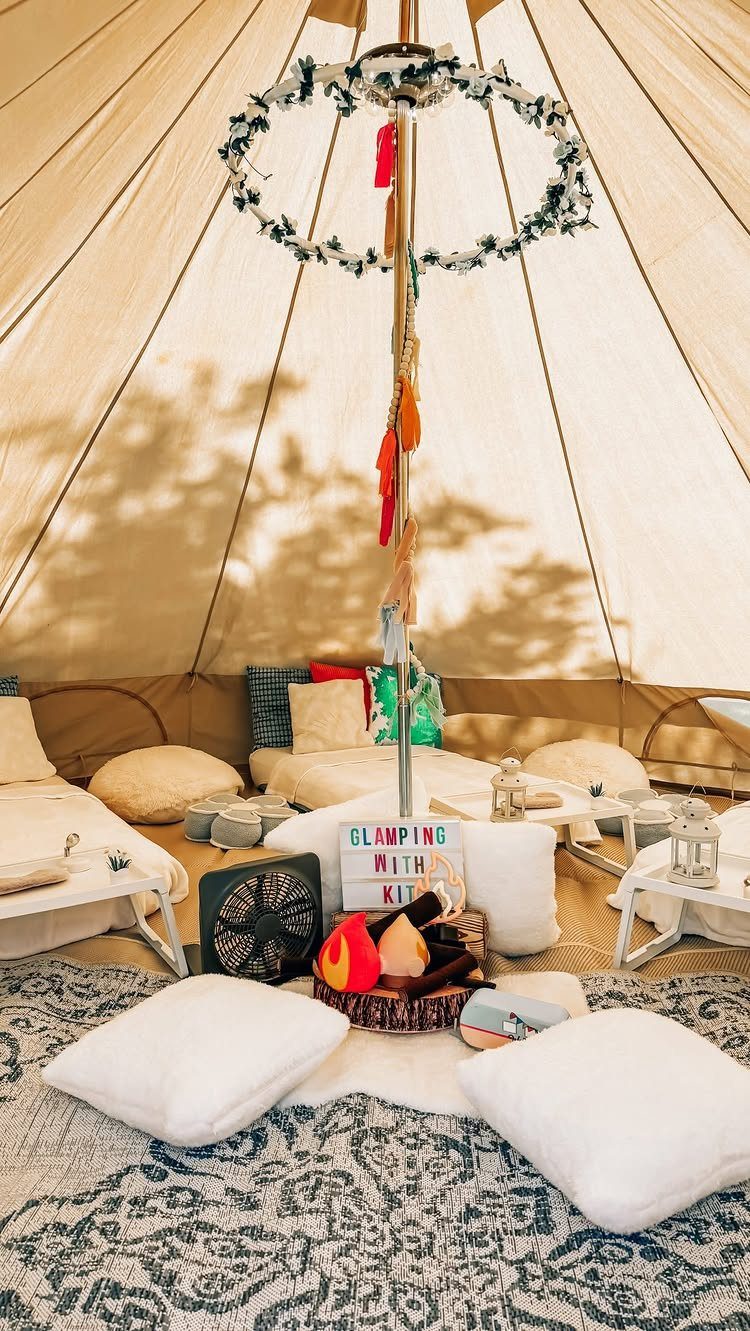 Interior of a glamping bell tent with white pillows, rugs, and decorative accents.