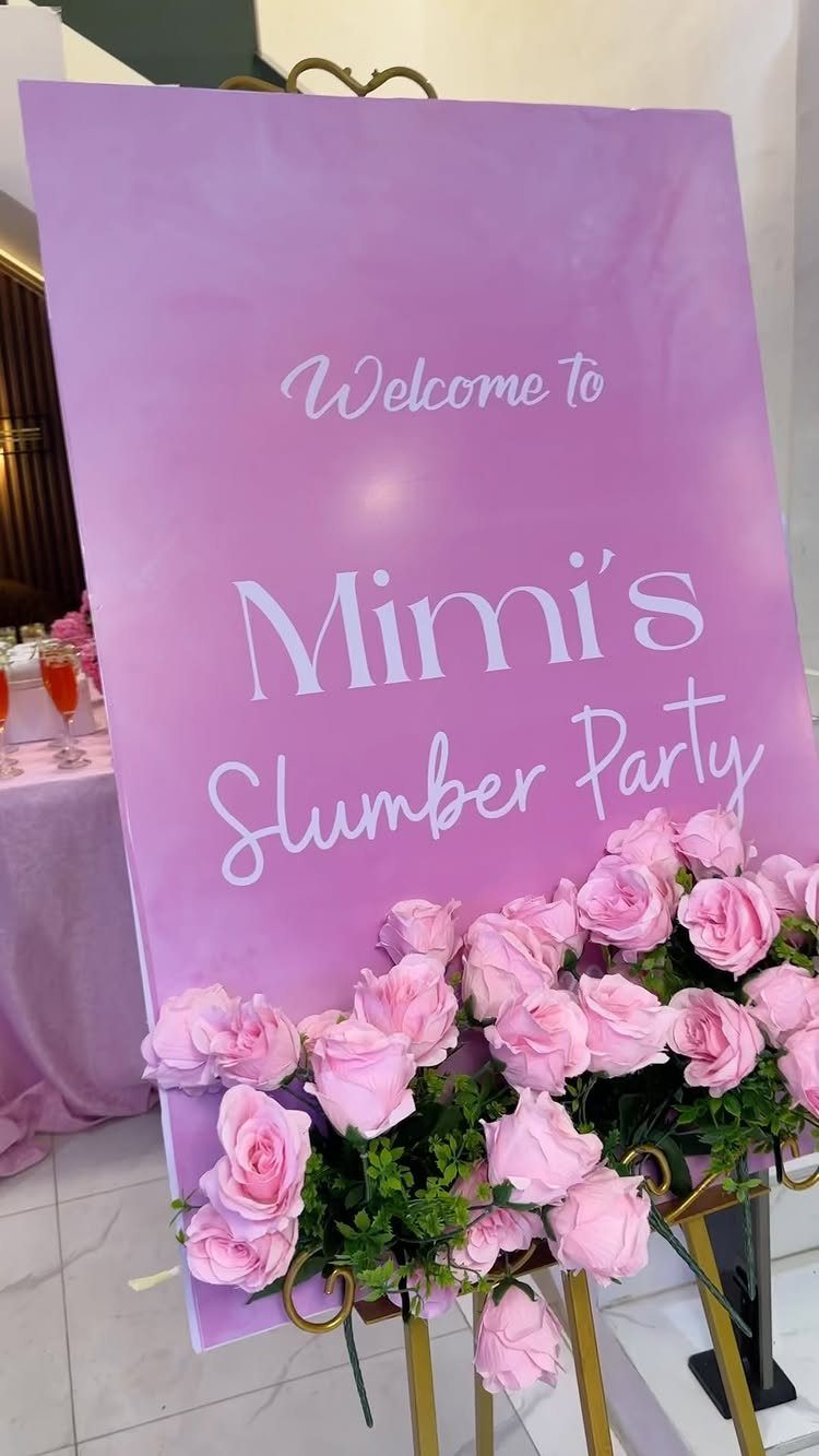 Purple welcome sign for Mimi's Slumber Party decorated with pink roses on a gold easel
