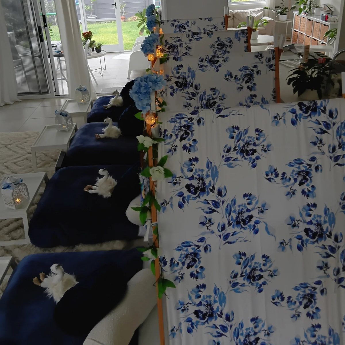 Blue floral bedding and mattresses arranged for a slumber party with fairy lights.