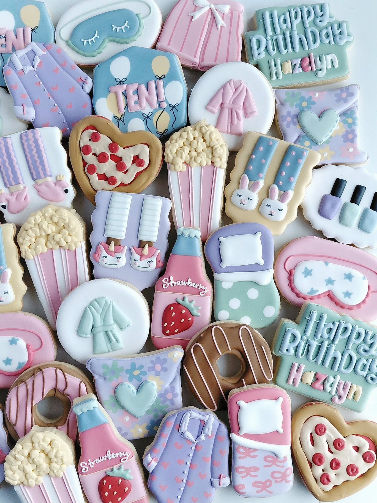 Pastel decorated sugar cookies shaped like sleepwear and snacks for a birthday party.