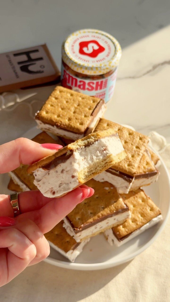 S'mores sandwiches on a white plate with a jar of spread in background.