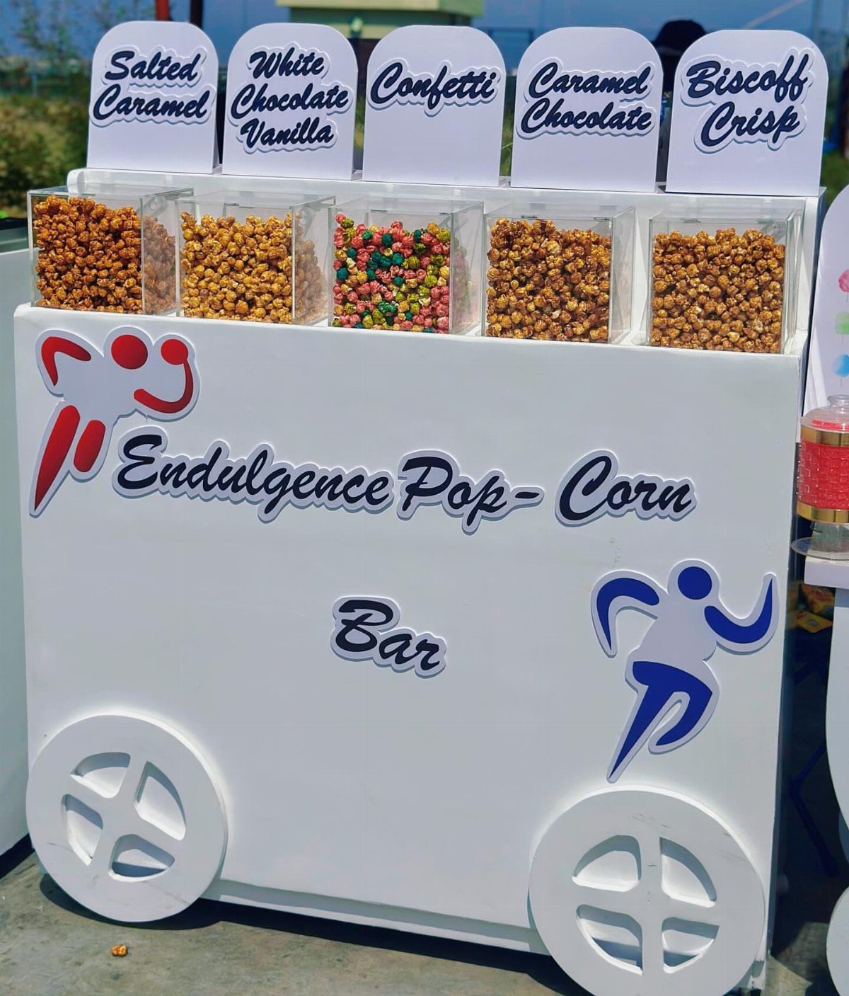 Popcorn buffet cart with five different flavored popcorns in clear bins with labels.