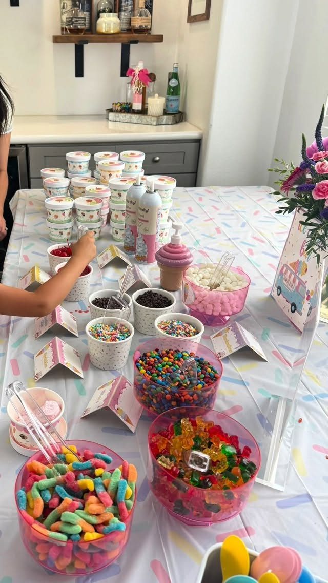 Candy buffet with colorful gummy worms and chocolates in bowls on a table.