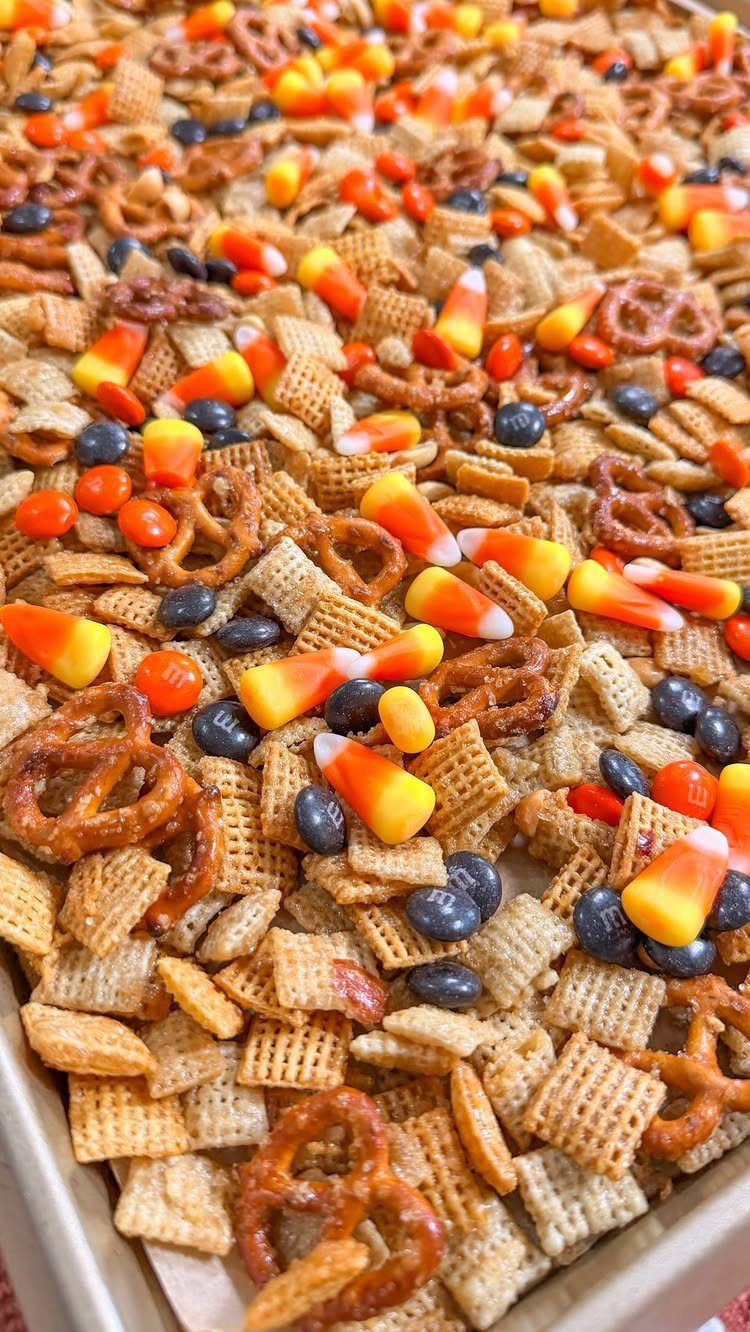 Snack mix with cereal, pretzels, and candy corn in a white tray.