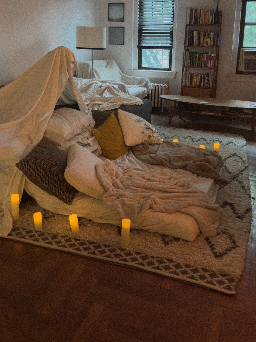 Blanket fort with pillows and candles on a rug in a living room