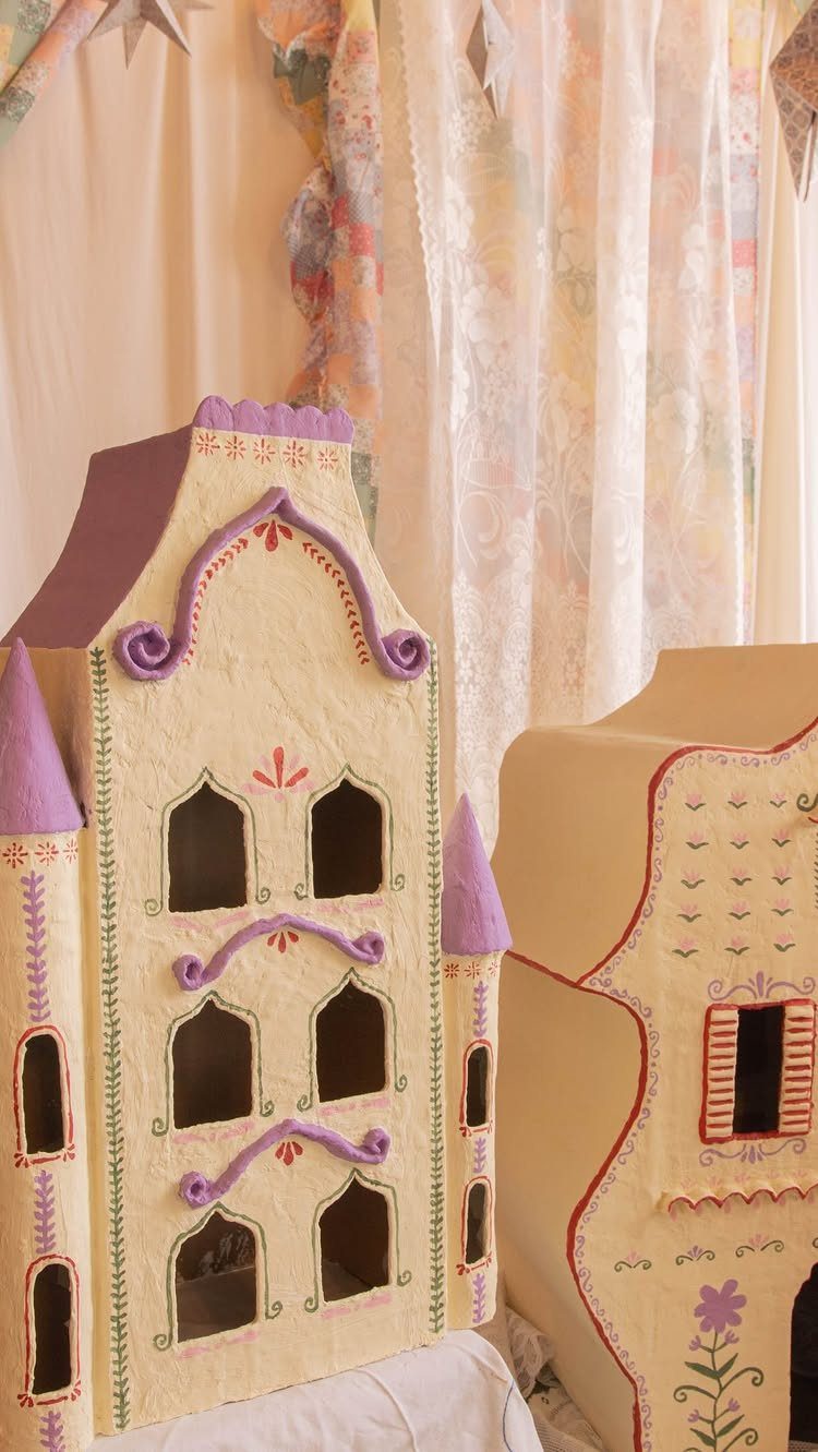 Cardboard playhouses designed as castles with purple roofs and hand-drawn floral details.