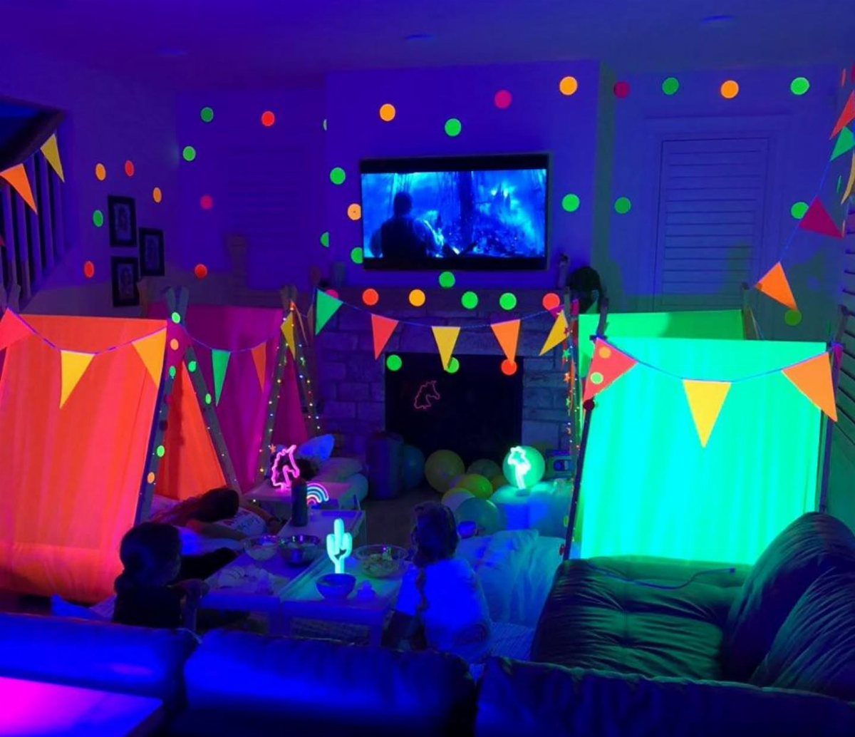 Neon glowing blanket forts in a living room with blacklight and fluorescent decorations.
