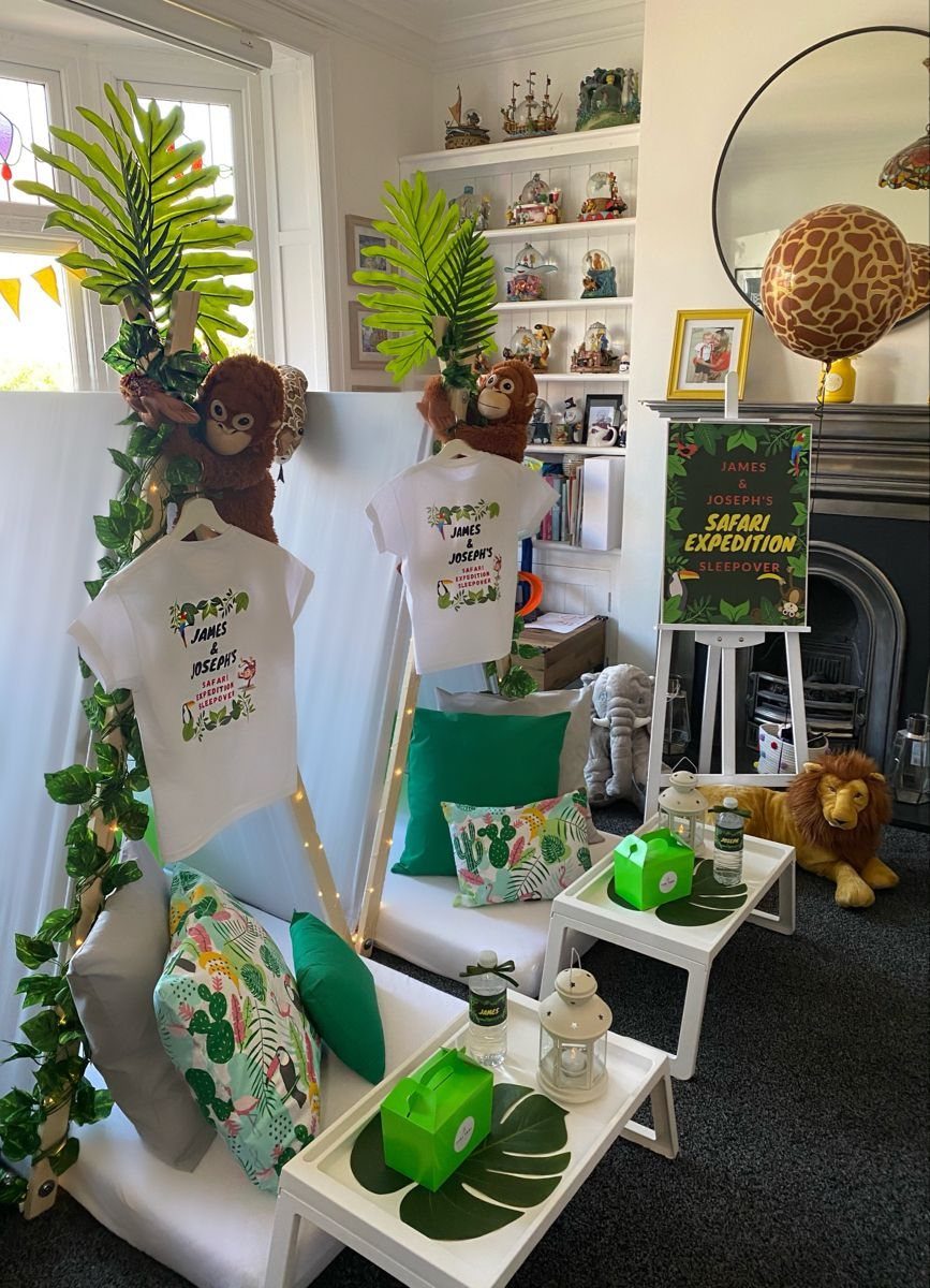 Two white teepee tents decorated with tropical leaves and safari animals for a party.