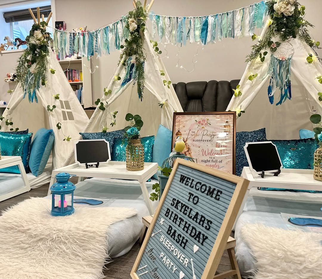 Three white teepee tents with blue decor and faux-fur rugs for a sleepover party.