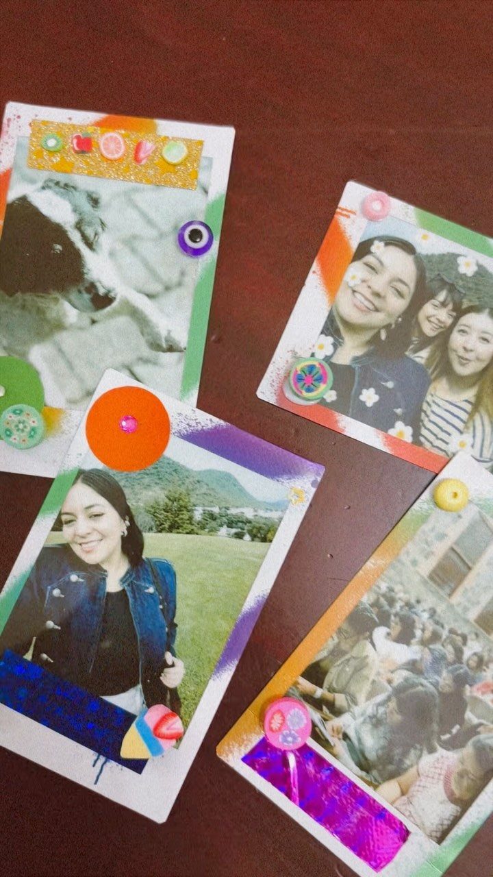 Handmade scrapbooked photos with colorful stickers and sequins on a dark wooden table.
