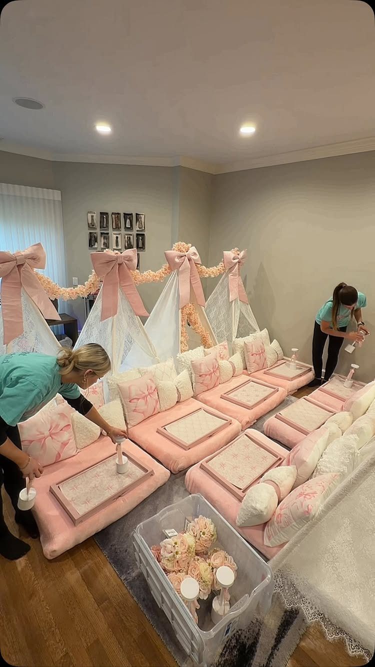 Pink mattresses and white teepee tents being set up for a slumber party.