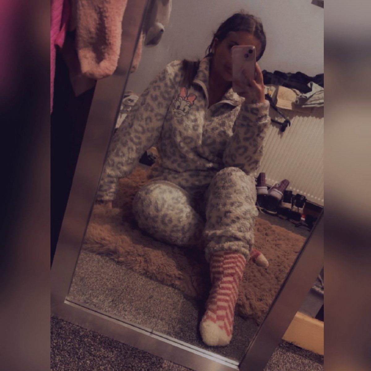 Person in fuzzy patterned pajamas and striped socks sitting on a shag rug.