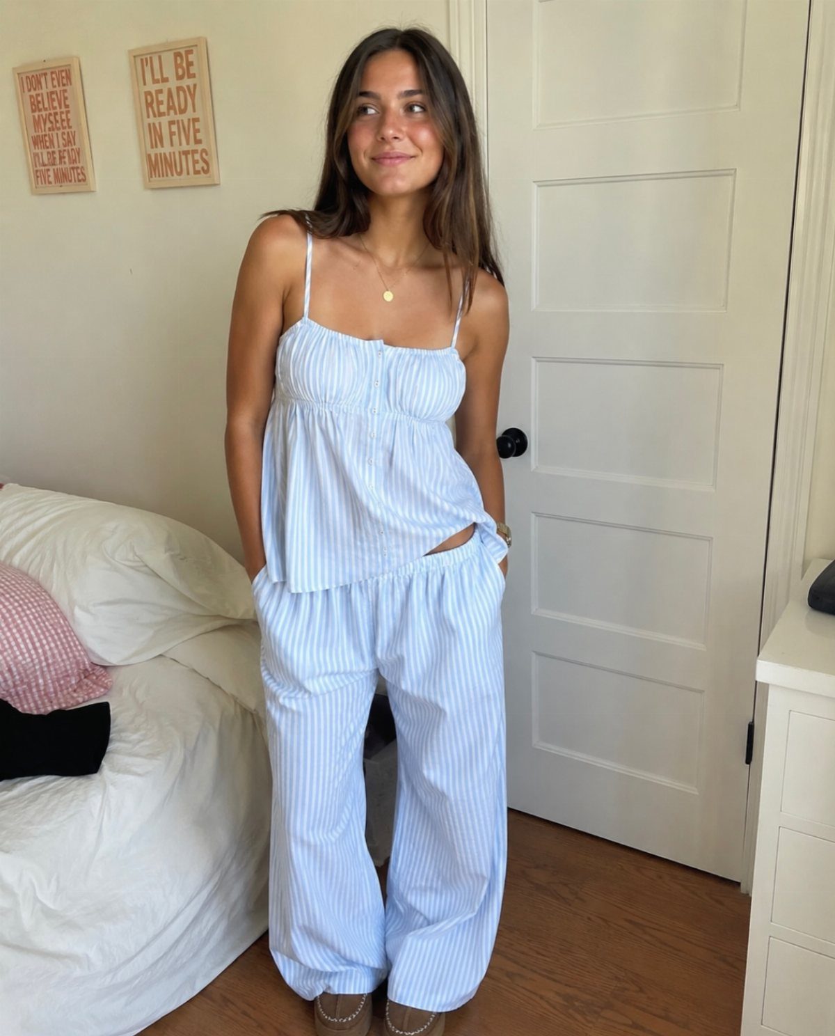 Young woman wearing blue and white striped pajama set in a bedroom setting.