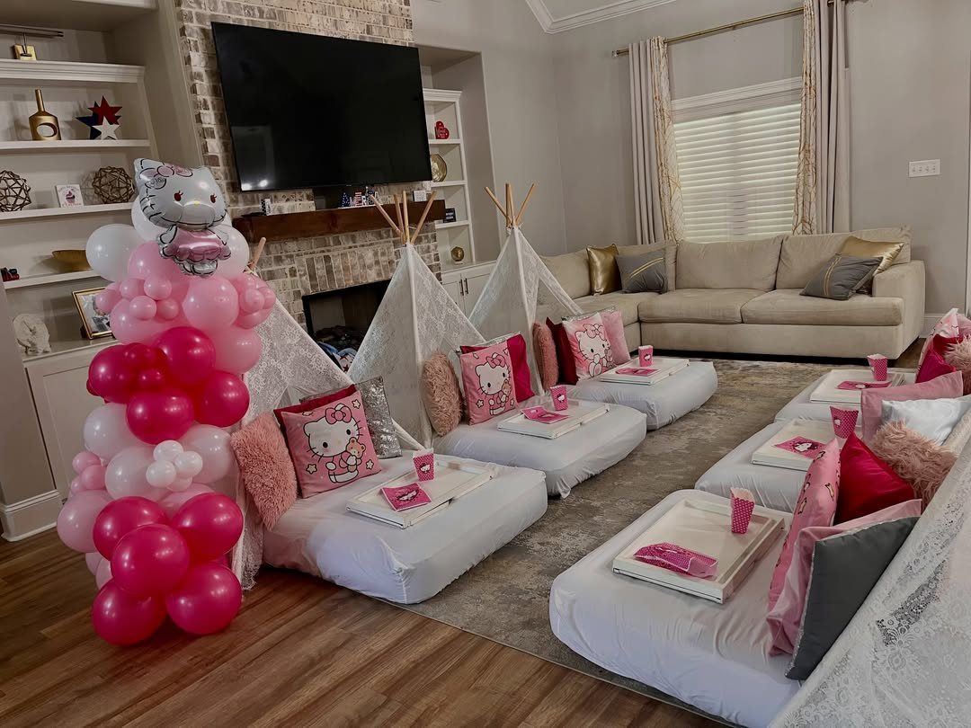 White lace teepees with pink Hello Kitty bedding and a pink balloon arch.