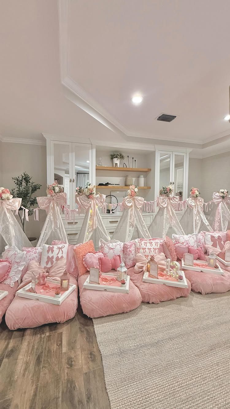 White teepees with pink bows and plush bean bags in a living room.