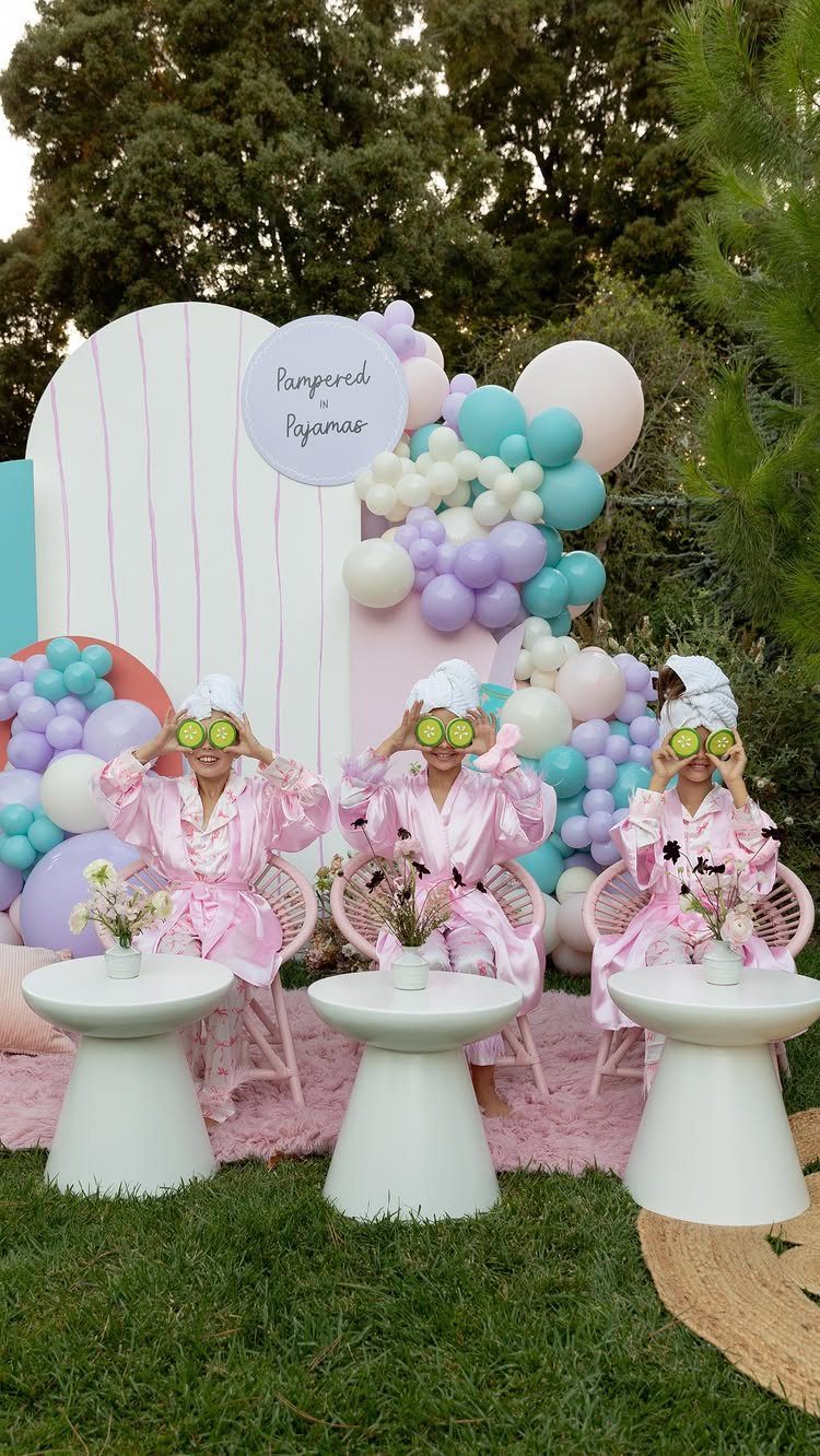 Three girls in pink robes with cucumber slices on eyes for spa night.