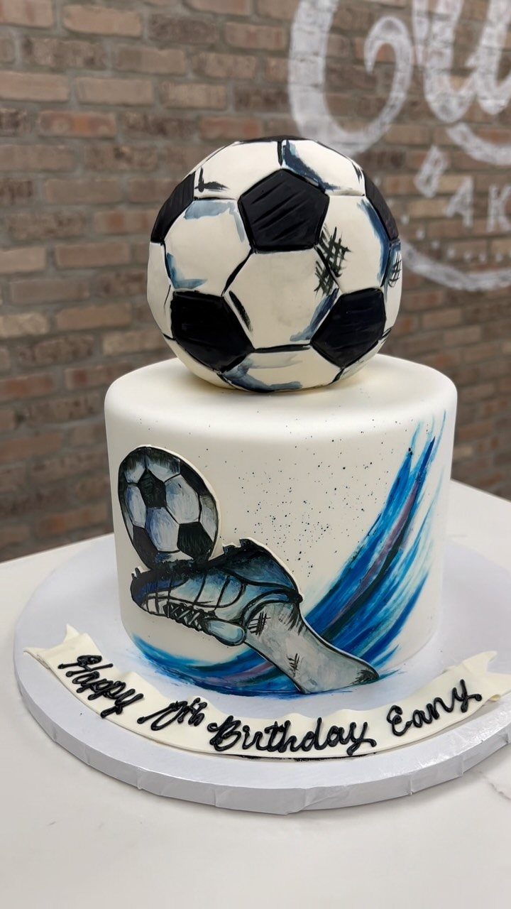 Two-tier soccer cake with a 3D soccer ball on top and painted details.