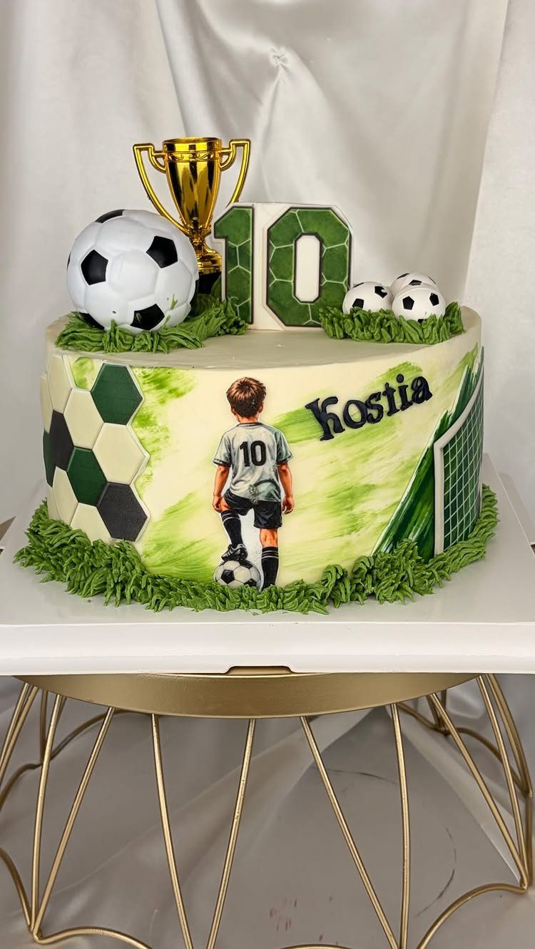 Soccer birthday cake with a gold trophy, soccer ball, and personalized name Kostia.