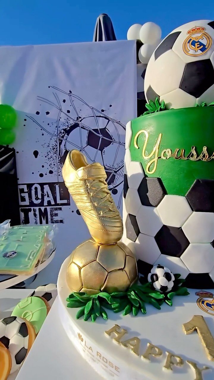 Multi-tiered soccer cake with gold cleat, gold ball, and soccer ball patterns.