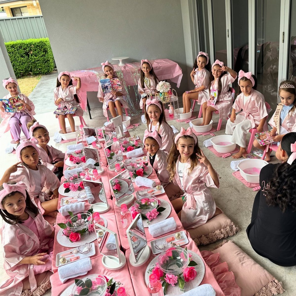 Girls in pink robes at a spa party with decorated table and foot basins.