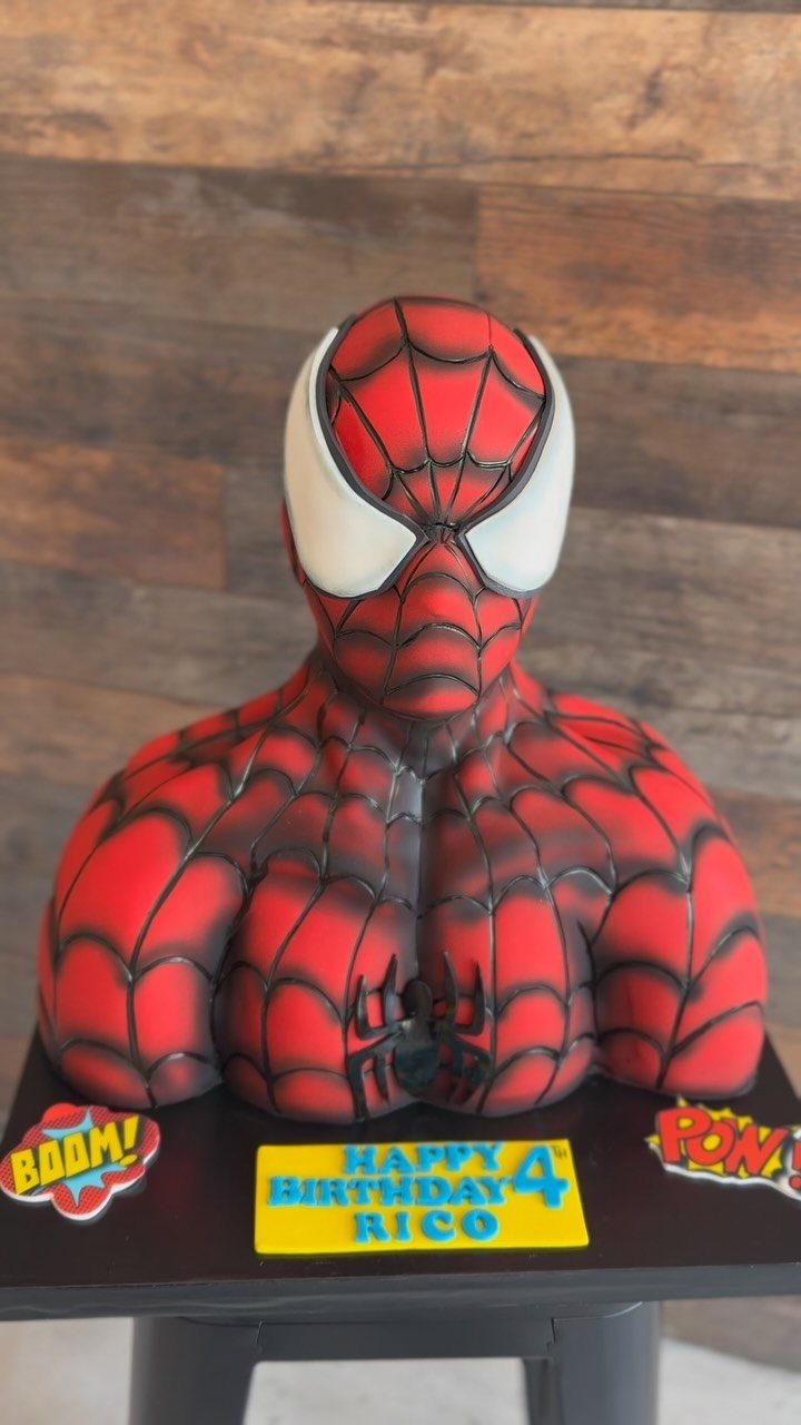 Spider-Man bust cake with red web design and birthday signs on black base