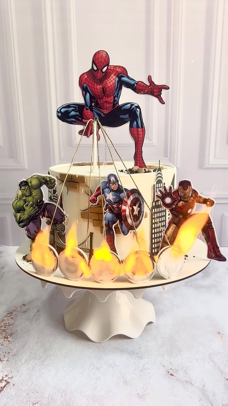 Spider-Man birthday cake with Avengers cutouts and flame decorations on a white stand