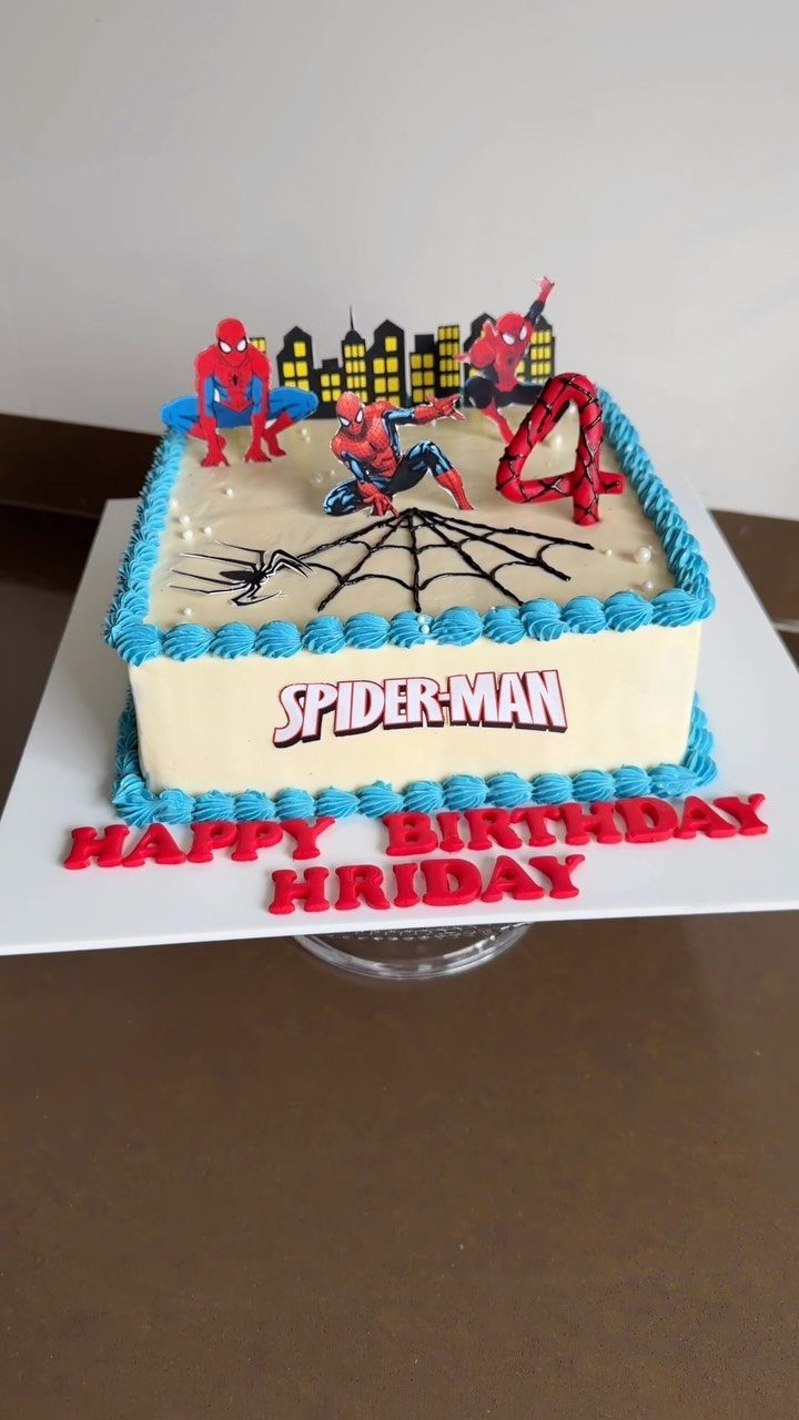 Square white buttercream cake with Spider-Man figurines, blue piping, and birthday text.