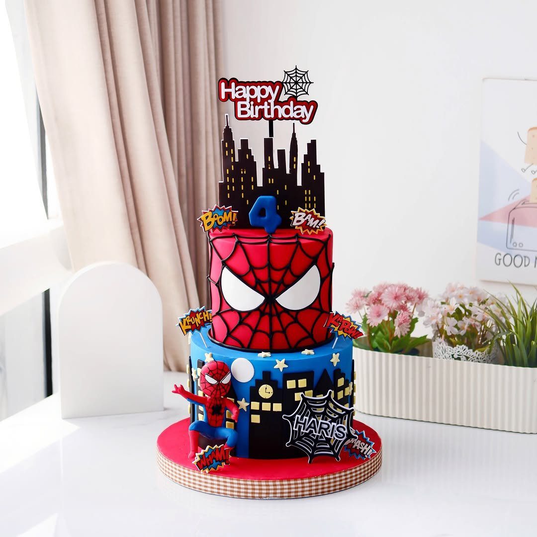 Two-tier Spider-Man cake with comic book expression toppers and a city skyline.