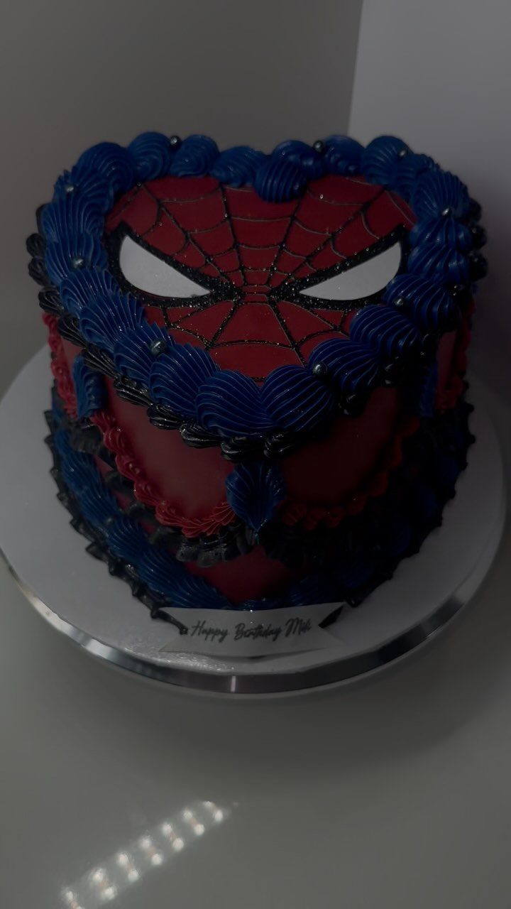 Red Spider-Man cake with a black web design and blue frosting borders.