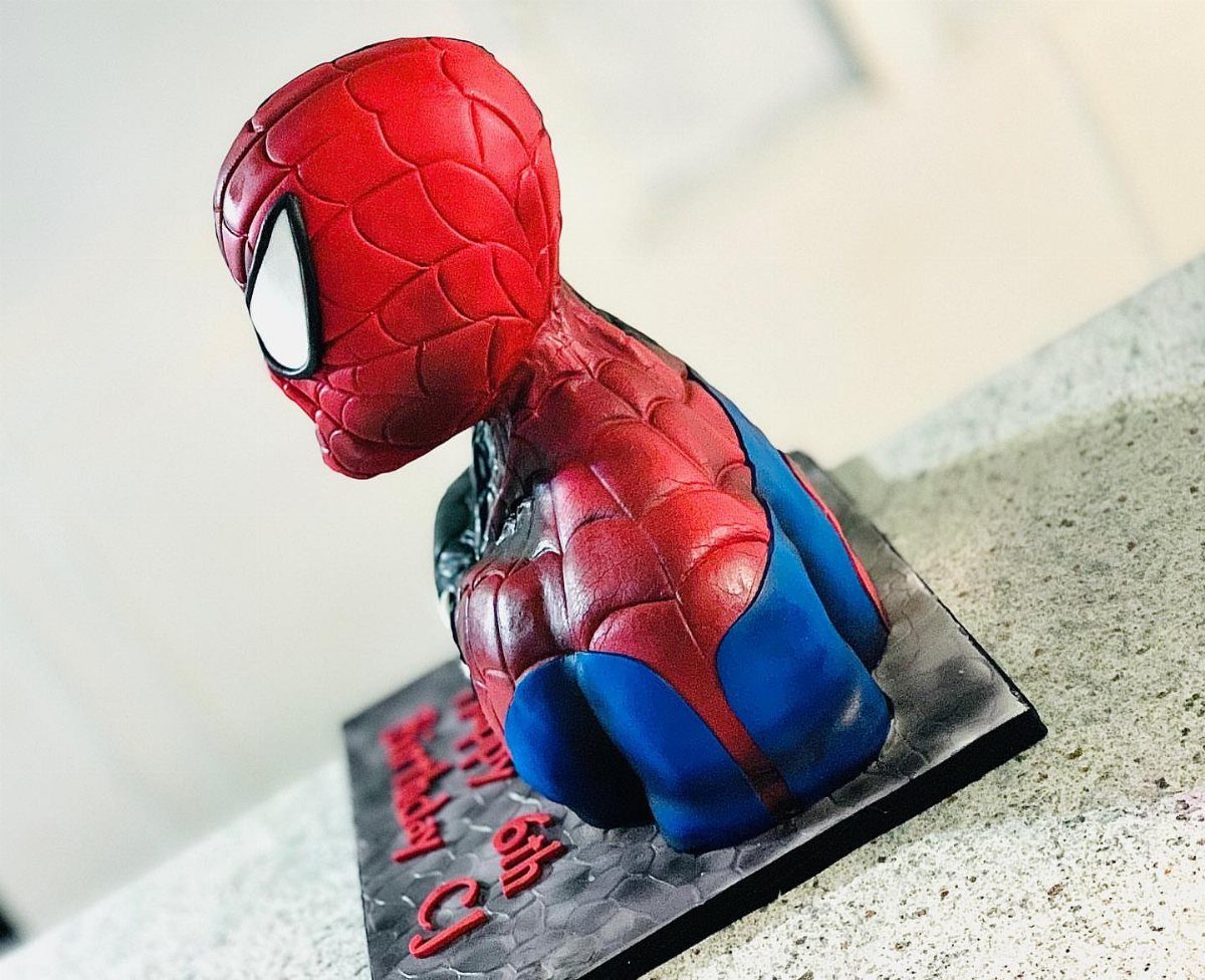 Spider-Man sculpted cake in a crouching pose on a black birthday base