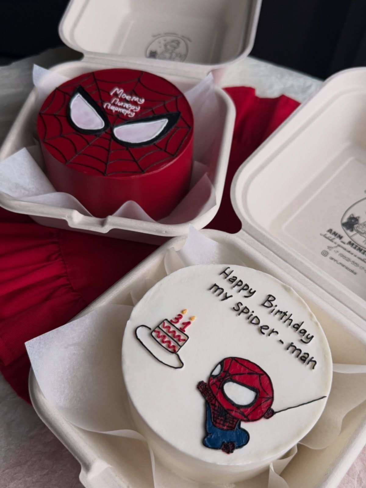 Two small Spider-Man birthday cakes, one red mask design and one white with illustration.