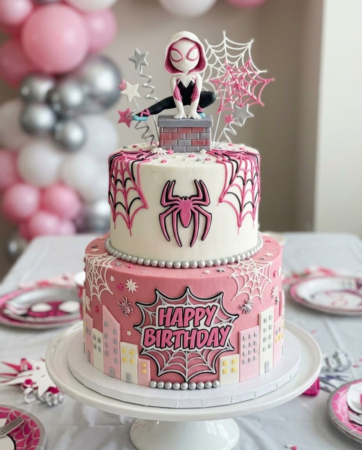 Two-tiered pink and white Ghost-Spider birthday cake with city skyline and web decorations