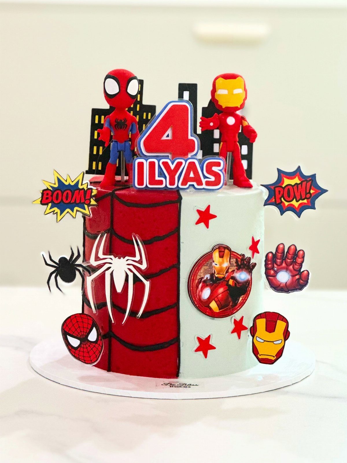 Spider-Man and Iron Man birthday cake with red and white frosting and toppers