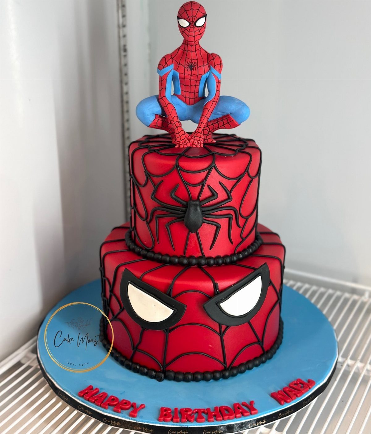 Two-tiered red Spider-Man cake with a 3D figure on top and birthday text.