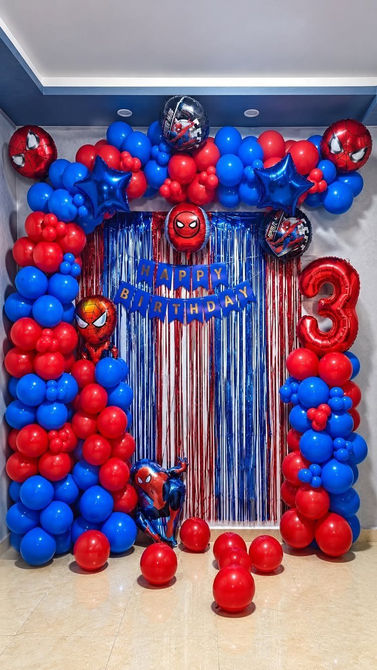 Spiderman balloon garland in red and blue framing a birthday party backdrop.